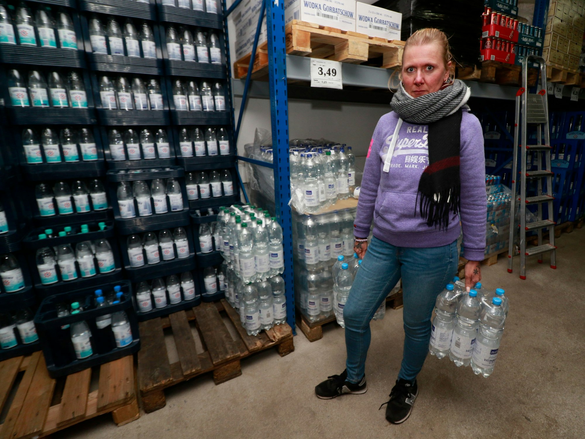 Eine Frau mit zwei Packungen Wasser in den Händen.
