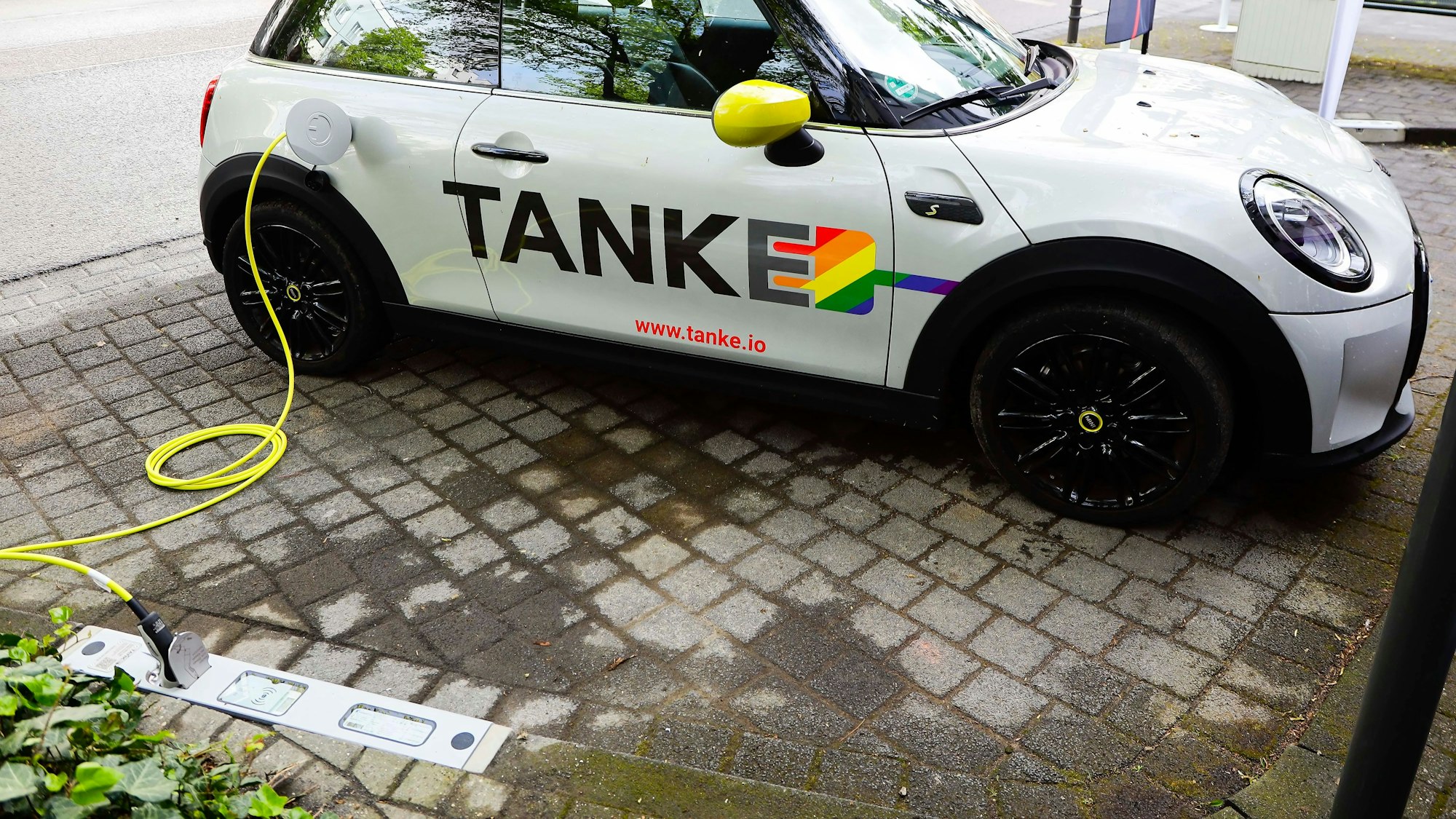 Ein Auto wird über einen Bordstein mit Strom betankt.