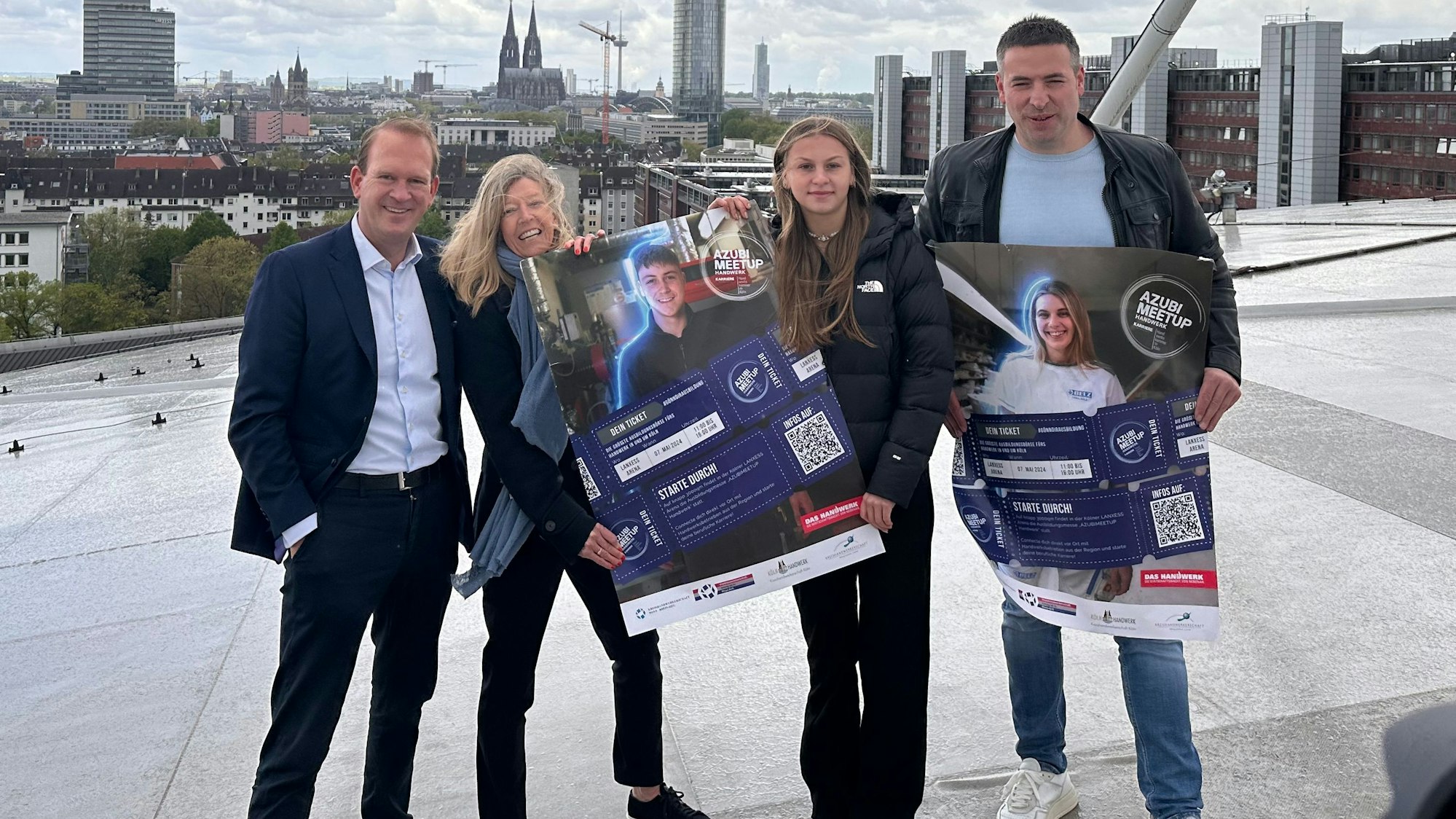 Zwei Männer und zwei Frauen auf dem Dach der Lanxess-Arena in Köln, sie zeigen Plakate.