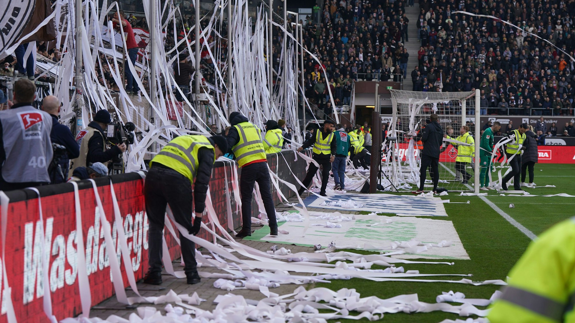 Ordner befreien das Spielfeld von Papierrollen.