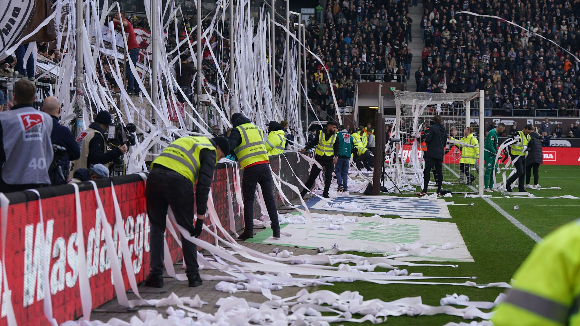 Ordner befreien das Spielfeld von Papierrollen.