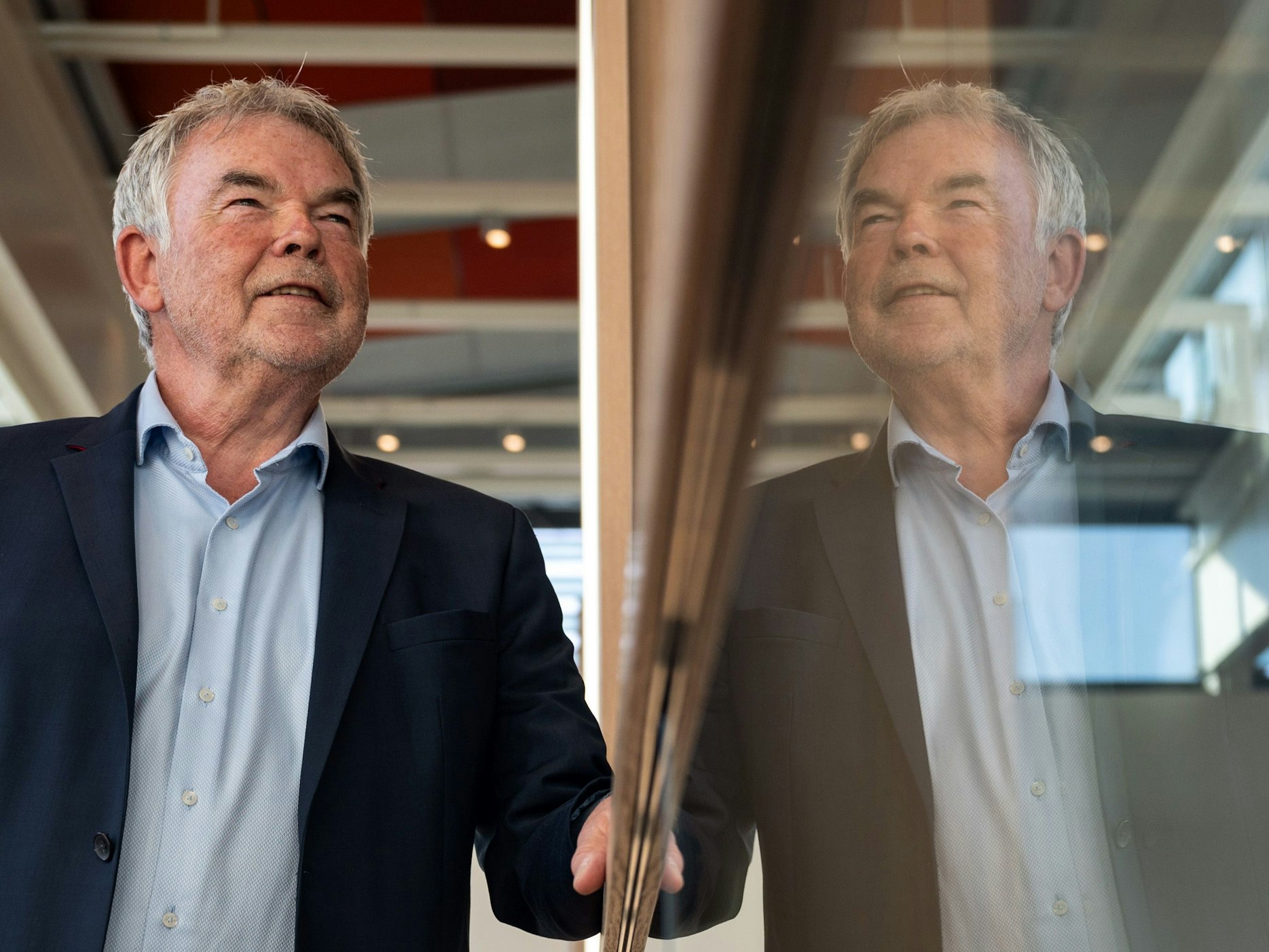 Der frühere Sportreporter Manfred „Manni“ Breuckmann spiegelt sich im Landgericht im gläsernen Geländer.