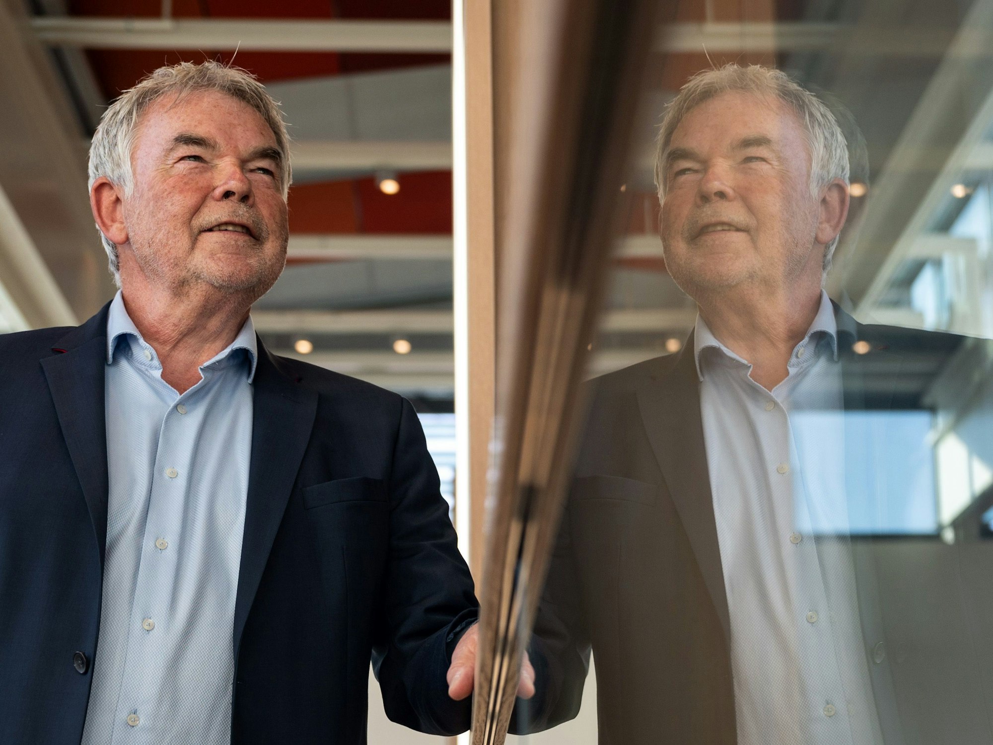 Der frühere Sportreporter Manfred „Manni“ Breuckmann spiegelt sich im Landgericht im gläsernen Geländer.