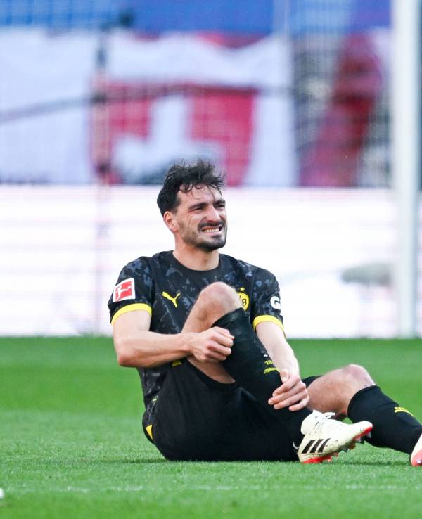 Mats Hummels sitzt mit schmerzverzerrter Miene auf dem Rasen und hält sich das rechte Schienbein.