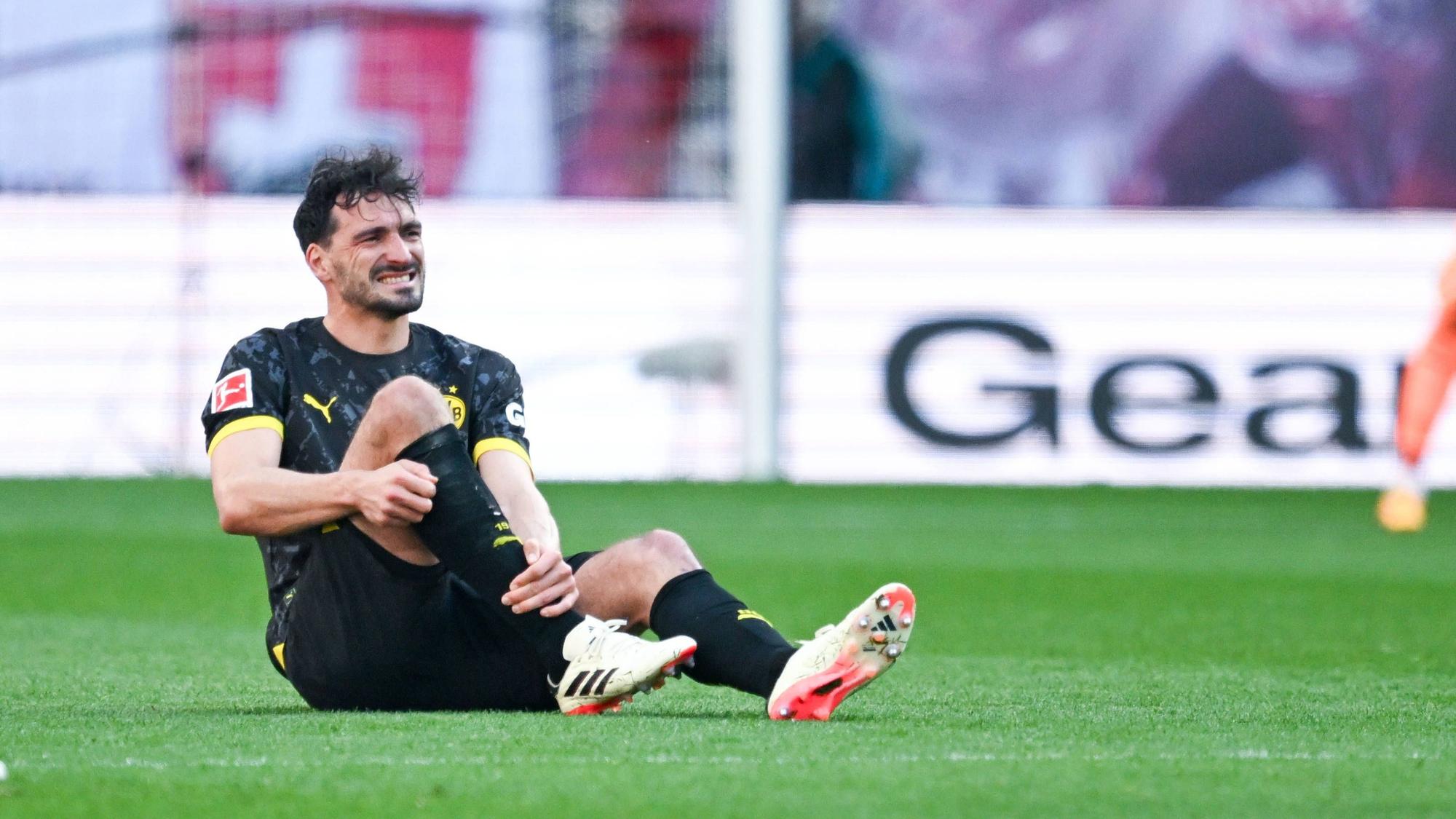 Mats Hummels sitzt mit schmerzverzerrter Miene auf dem Rasen und hält sich das rechte Schienbein.