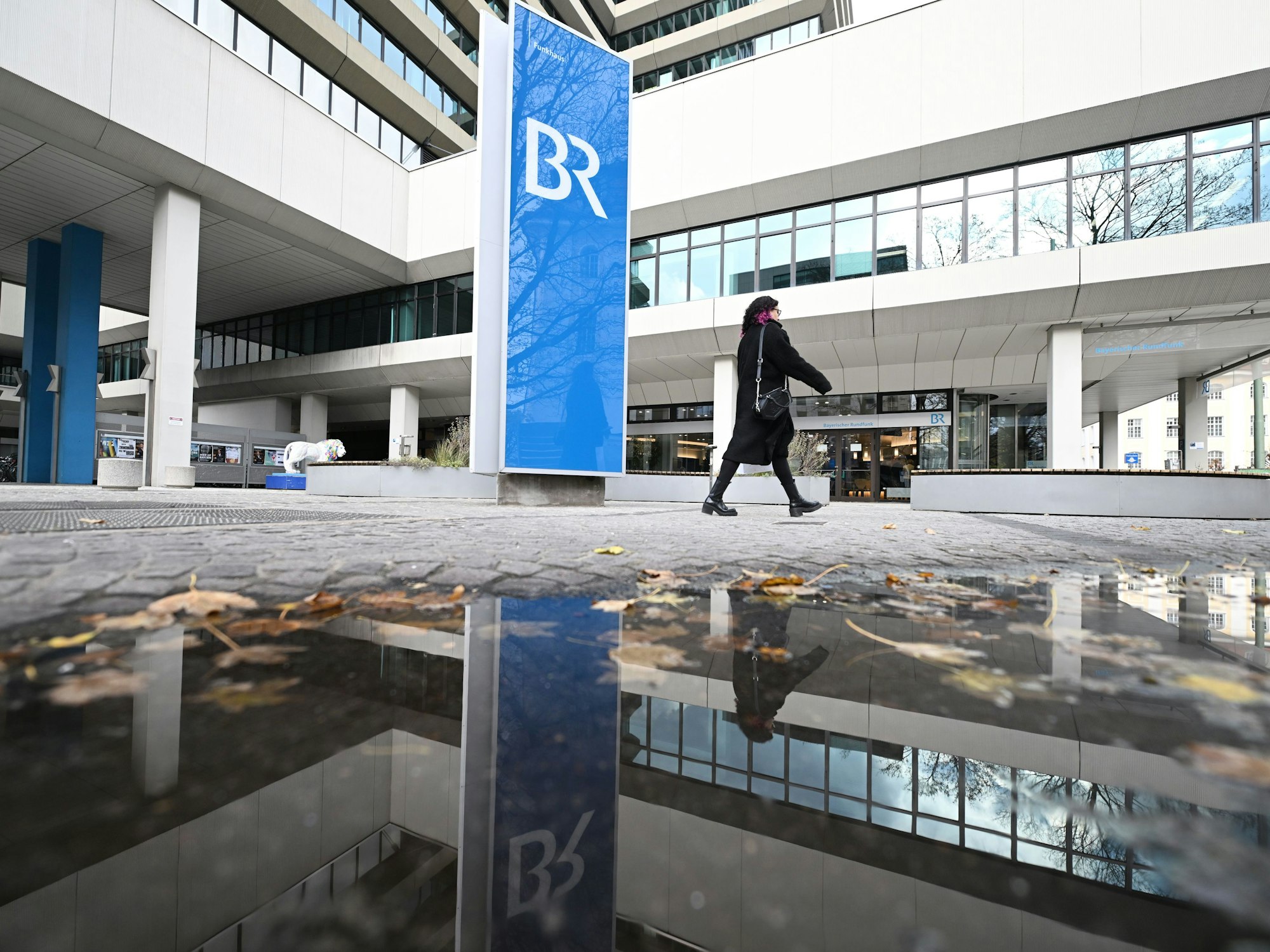 Das Logo des Bayerischen Rundfunks (BR) spiegelt sich in einer Regenpfütze.