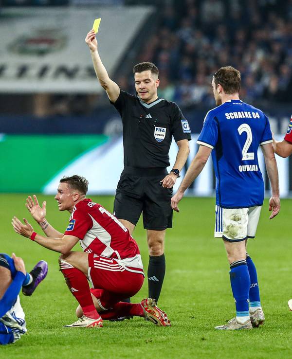 Fortuna Düsseldorfs Felix Klaus kniet am Boden, Schiedsrichter Harm Osmers zeigt ihm die Gelbe Karte.