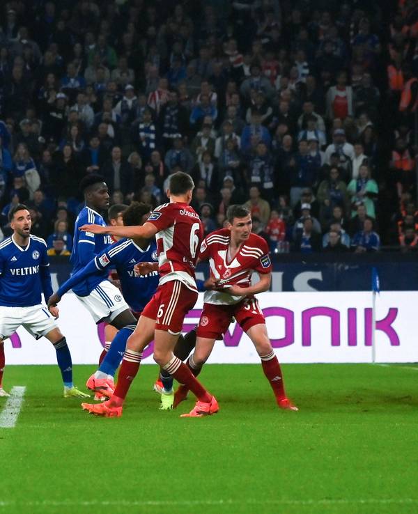 Fortuna Düsseldorf und Schalke 04 Spieler schauen auf den Ball, der den Pfosten vom Tor trifft.