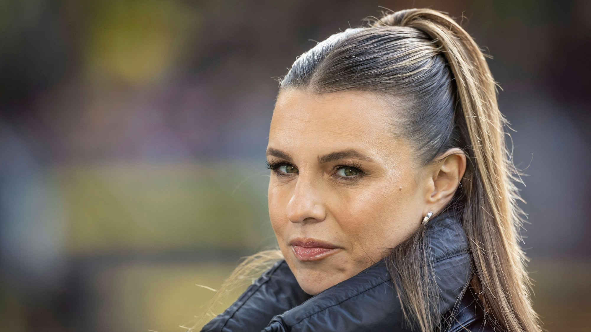 Laura Wontorra blickt am Rande einer TV-Übertragung von DAZN in die Kamera.