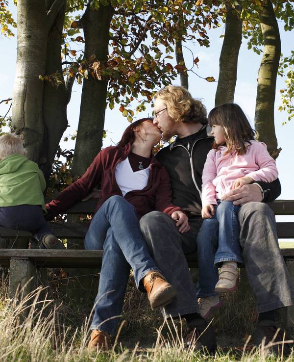 Junge Familie sitzt auf einer Bank