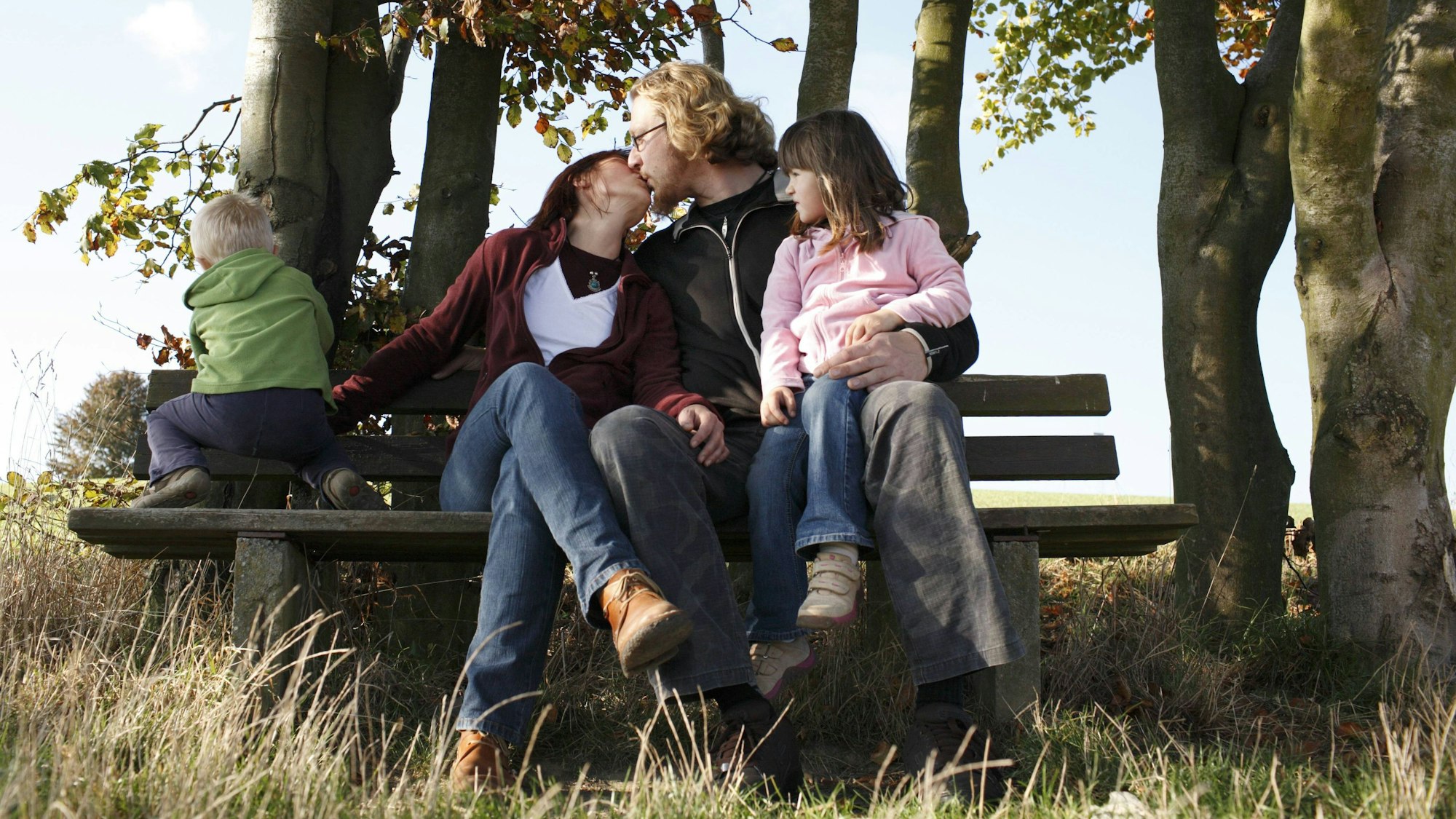 Junge Familie sitzt auf einer Bank