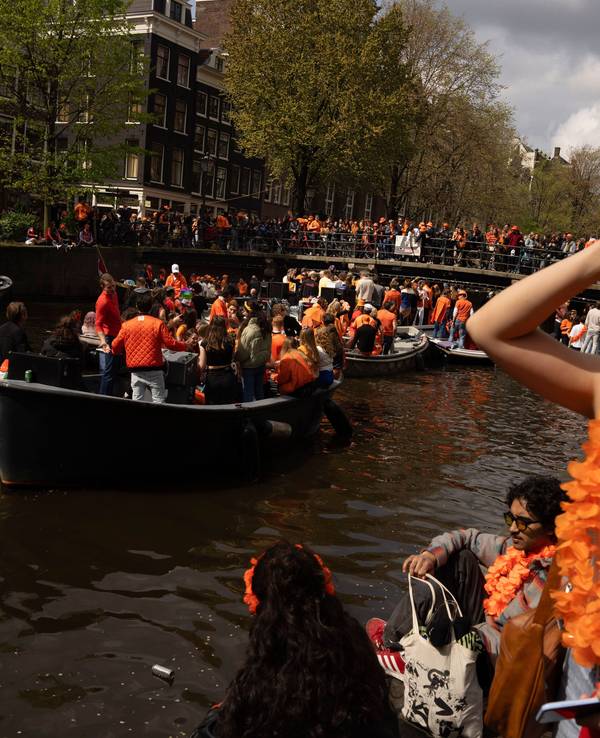 Menschen feiern den Königstag in den Grachten von Amsterdam.