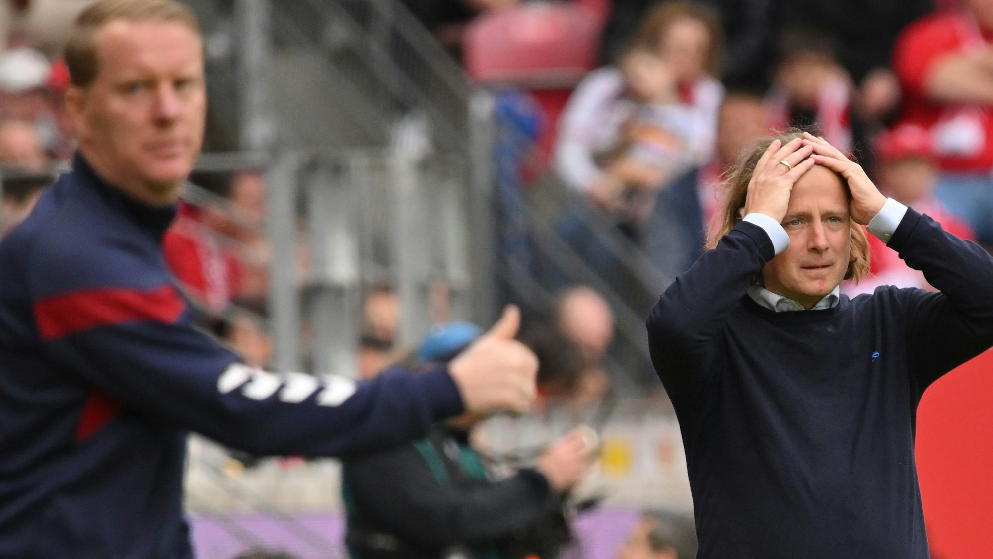 Der Mainzer Trainer Bo Henriksen (r) reagiert neben Kölns Trainer Timo Schultz.