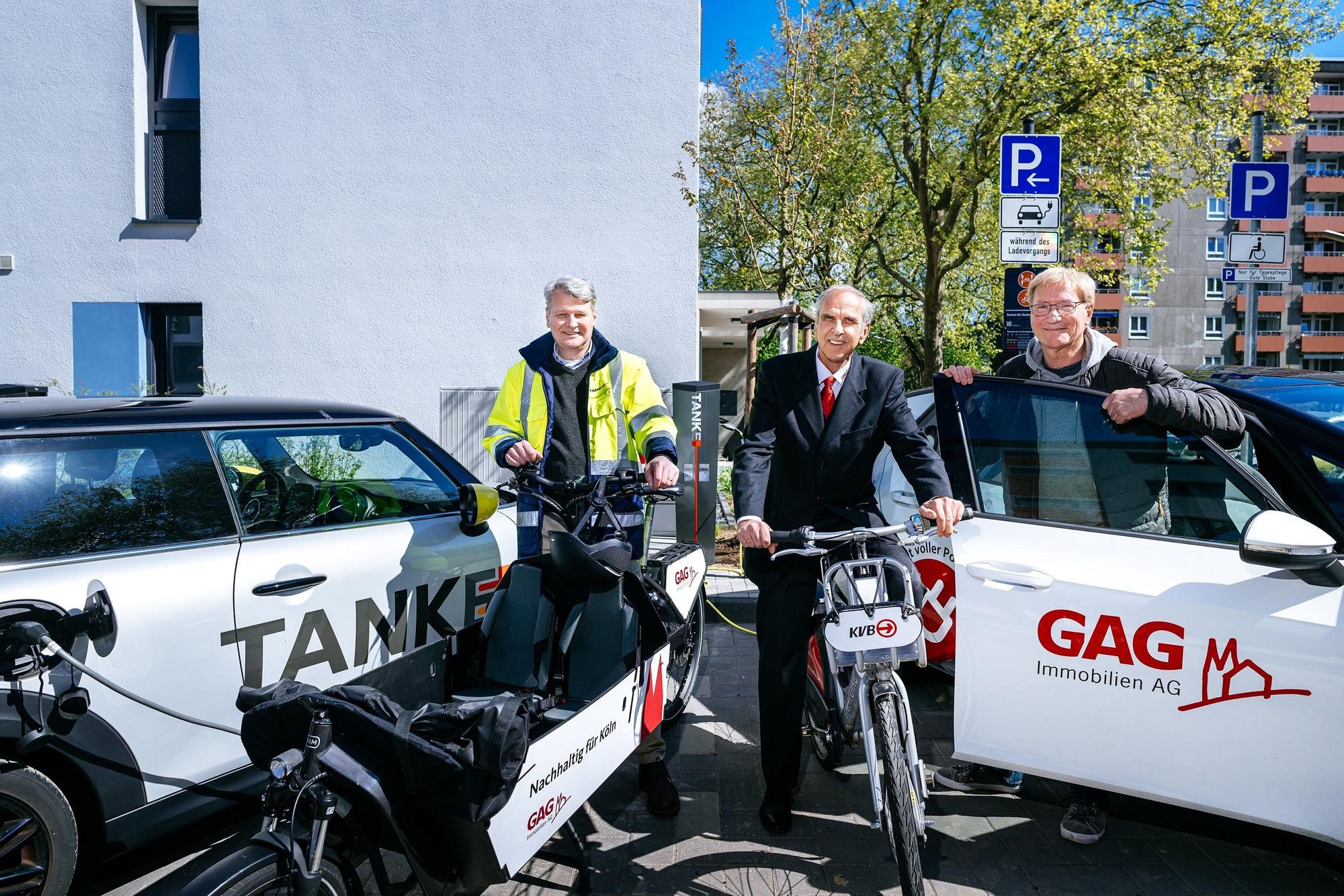 Jörn Hansen (TankE, links), Bernd Gräber (GAG, Mitte) und Frank Wendler (KVB, rechts) eröffnen den Mobilitäts-Hub mit Ladesäulen für E-Pkw, KVB-Rädern und GAG-Lastenrad in der Kannebäckersiedlung in Humbold/Gremberg.