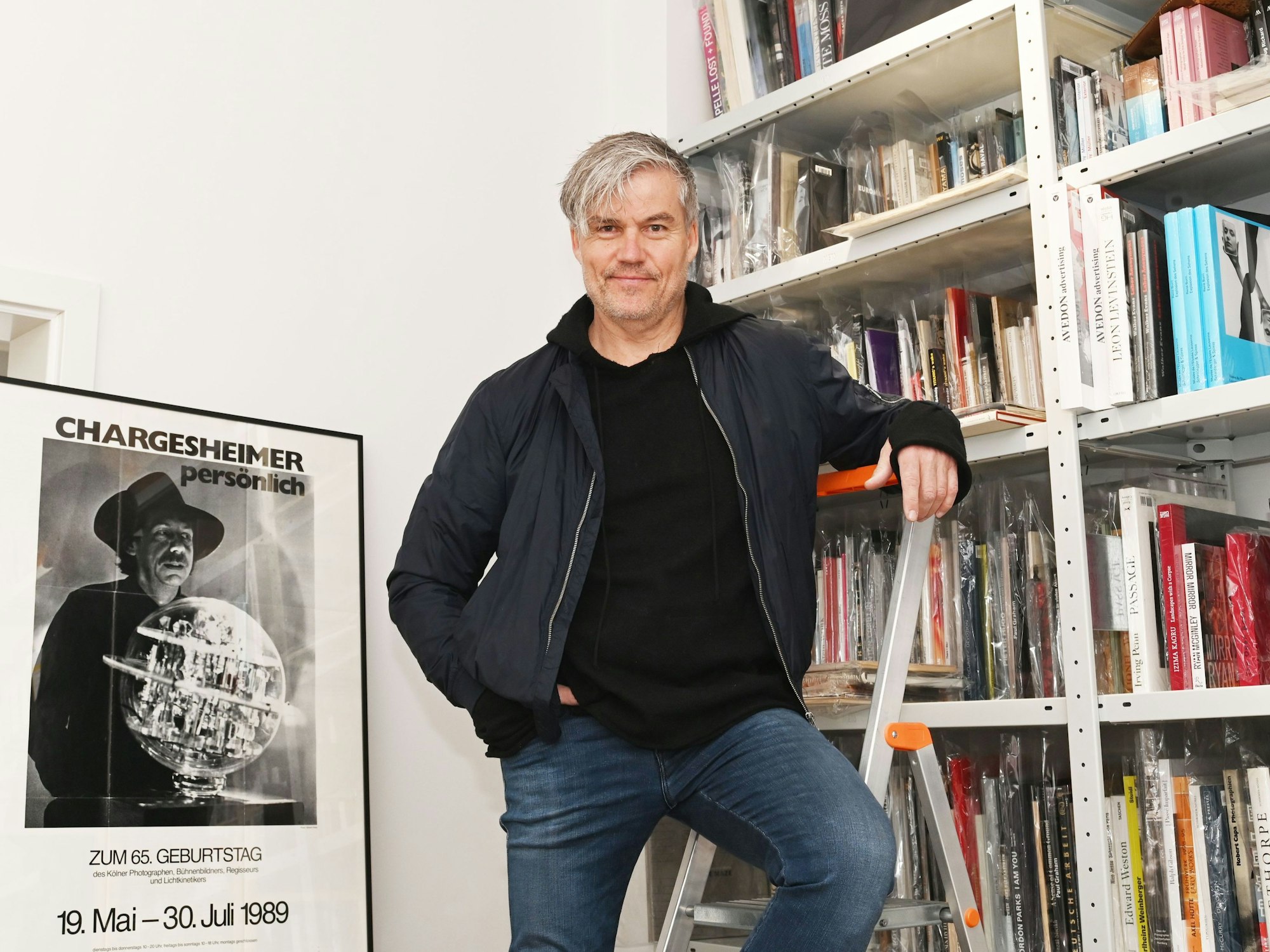 Ecki Heuser steht vor einem Bücherregal.