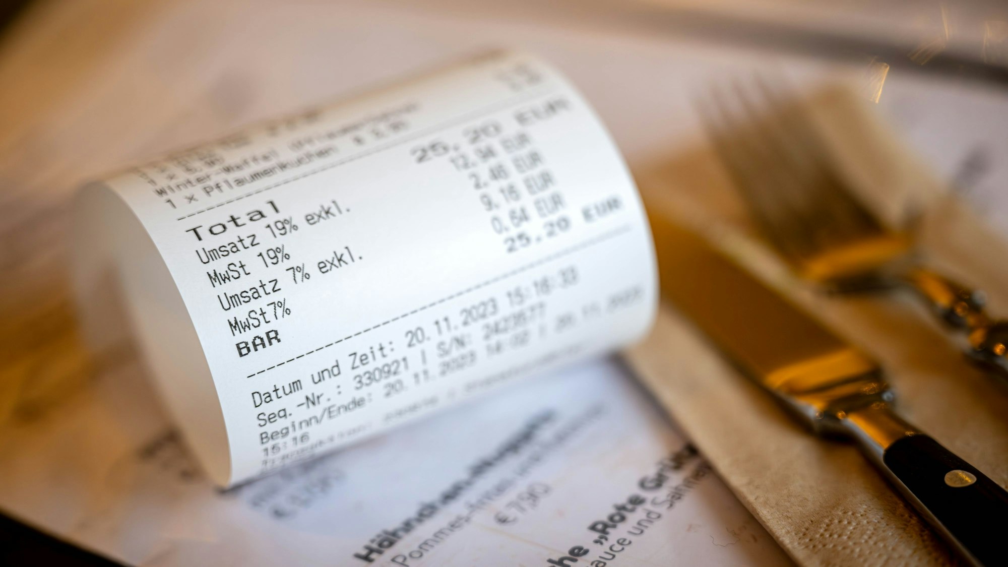 Eine Rechnung mit Umsatzsteuer und Mehrwertsteuer liegt auf der Speisekarte eines Restaurants.