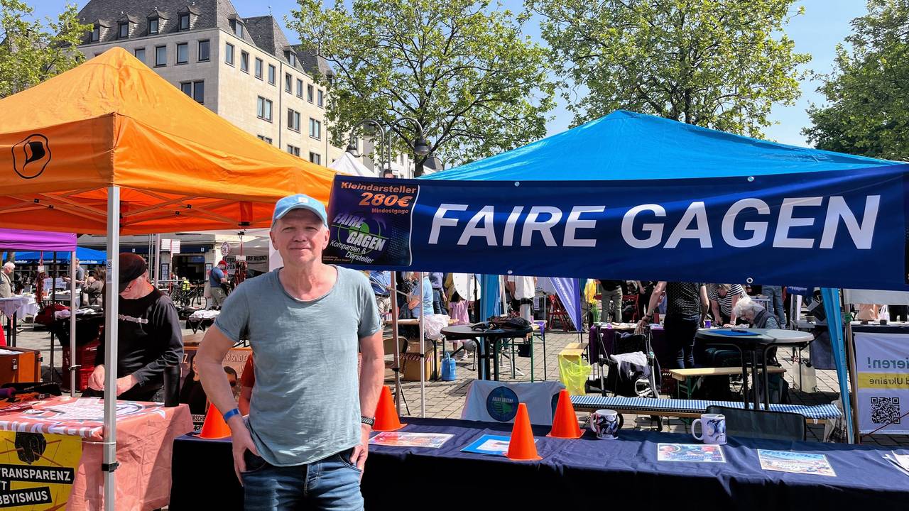 Klaus Stutzer steht vor dem Stand der Initiative „Faire Gagen“.