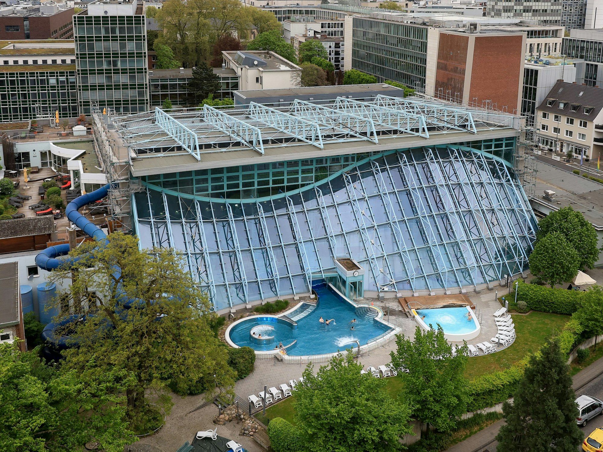 Blick aus der Luft auf das Agrippabad in Köln und die prägnante Glasfassade.