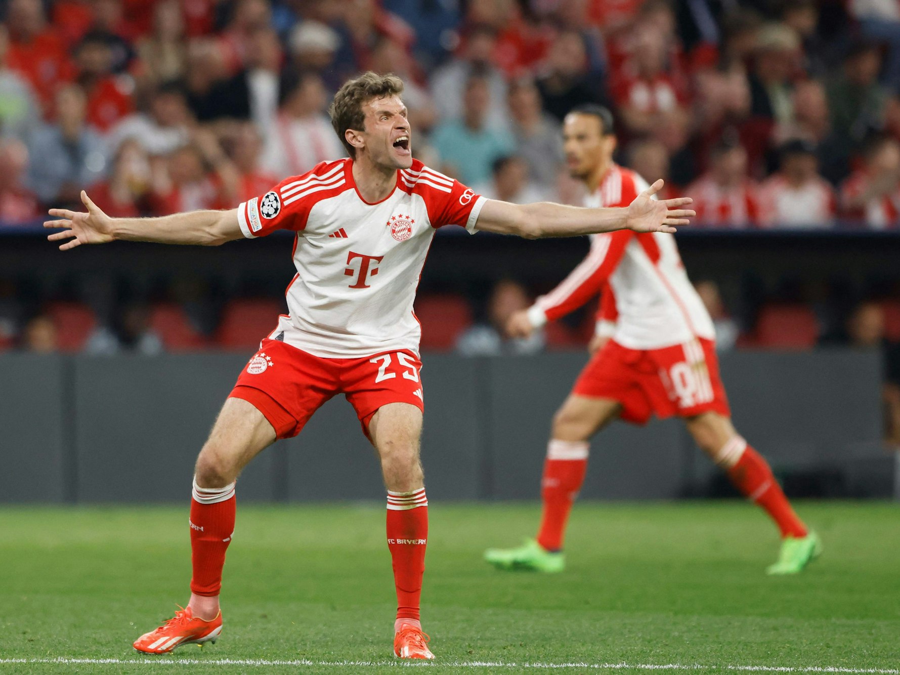 Thomas Müller steht auf dem Platz, breitet die Arme aus und brüllt.