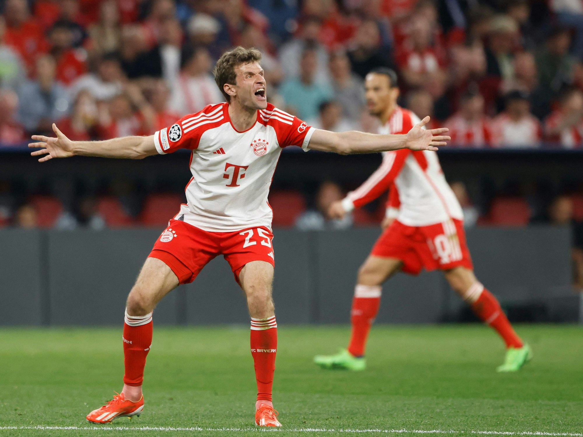 Thomas Müller steht auf dem Platz, breitet die Arme aus und brüllt.