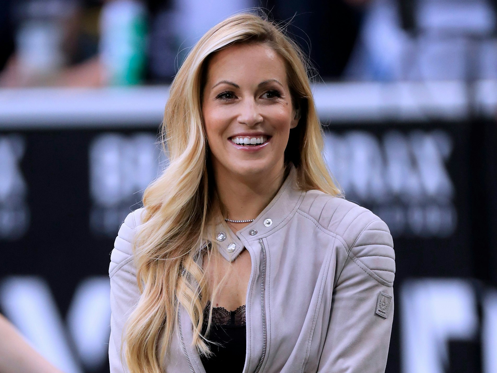 Sport-Moderatorin Andrea Kaiser lächelt am Spielfeldrand.