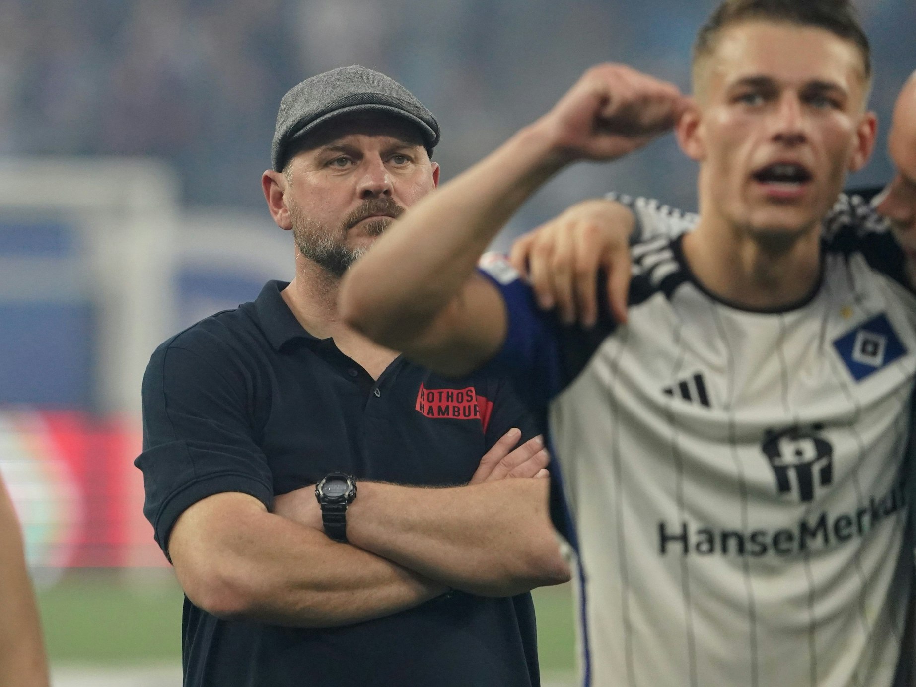 Steffen Baumgart verfolgt mit verschränkten Armen, wie seine Spieler sich nach dem Derbysieg von den Fans feiern lassen.