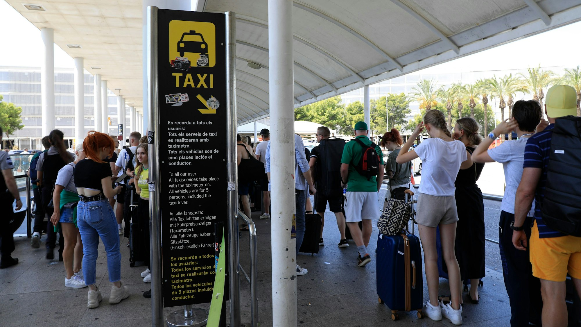 Reisende stehen am Flughafen von Mallorca in einer Schlange und warten auf Taxis.