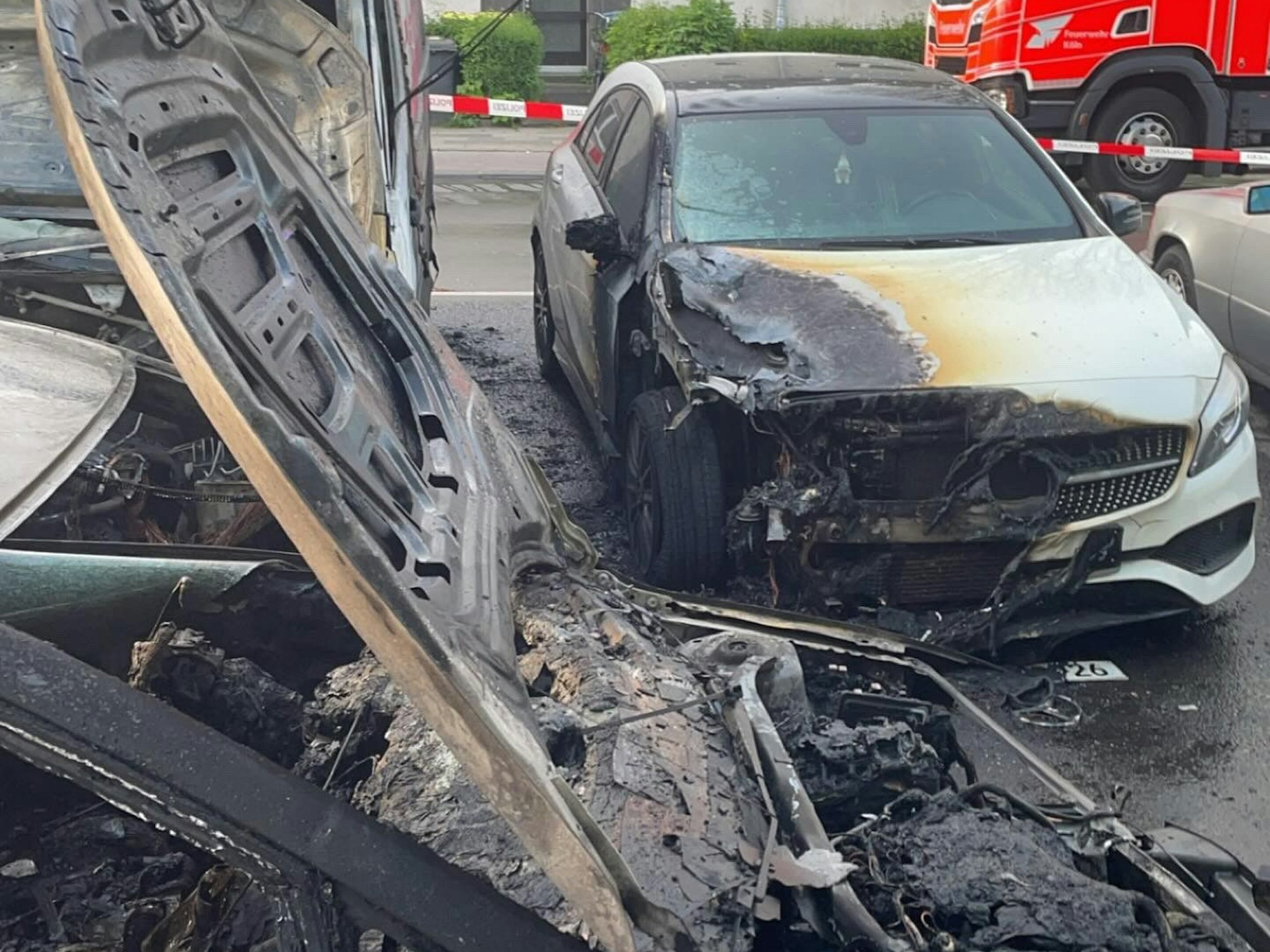 Zwei Autos stehen auf der Straße und sind fast komplett ausgebrannt.