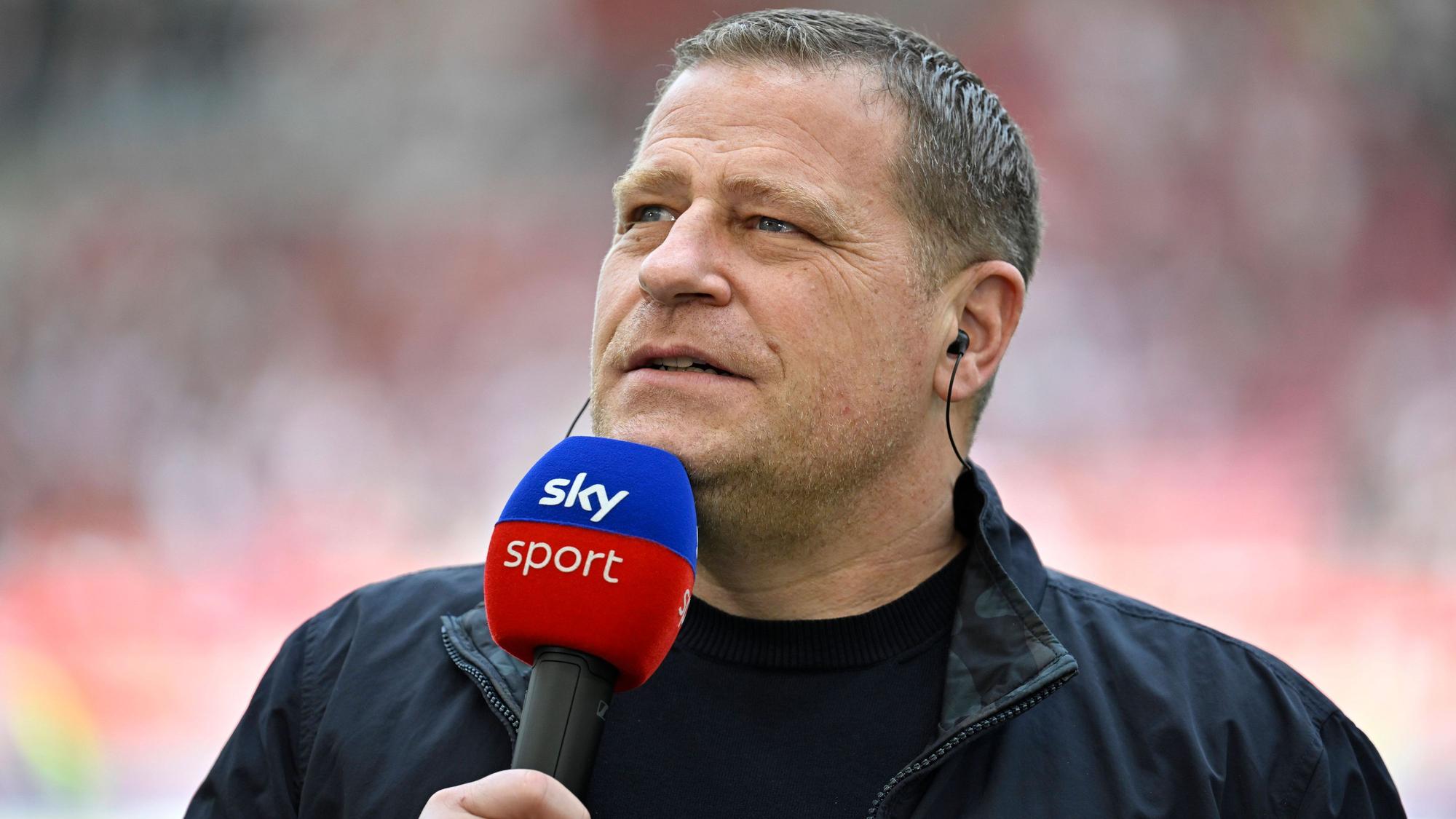 Max Eberl steht mit Mikrofon am Spielfeldrand.