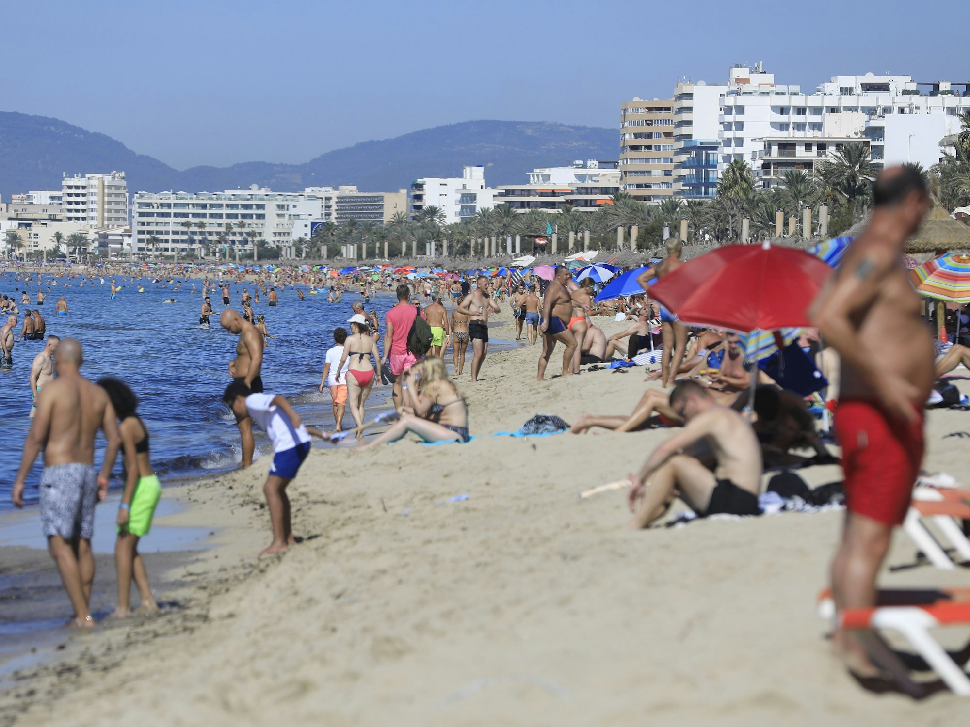 Urlauberinnen und Urlauber am Strand von Mallorca.
