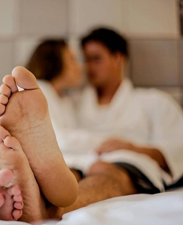 Paar im Bett mit ausgestreckten Füßen
