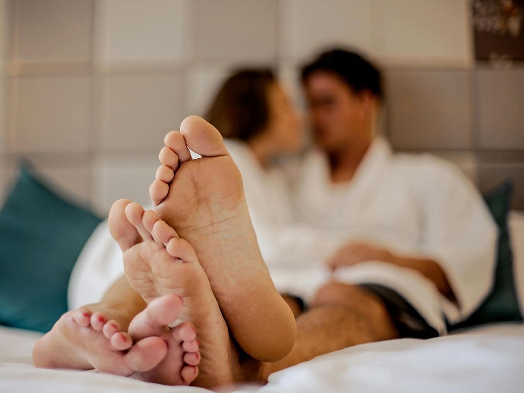 Paar im Bett mit ausgestreckten Füßen