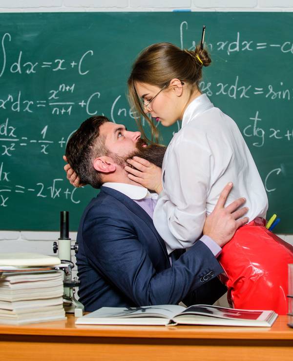 Lehrer und Schülerin flirten vor der Tafel.