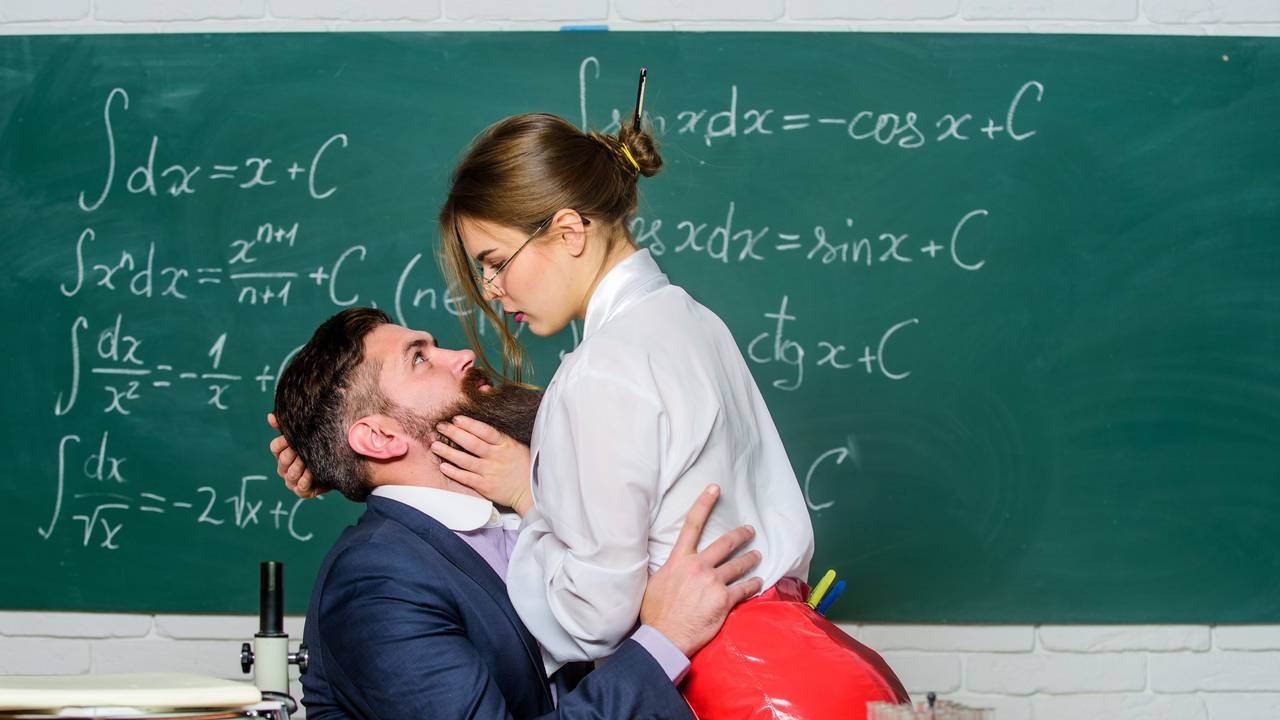 Lehrer und Schülerin flirten vor der Tafel.