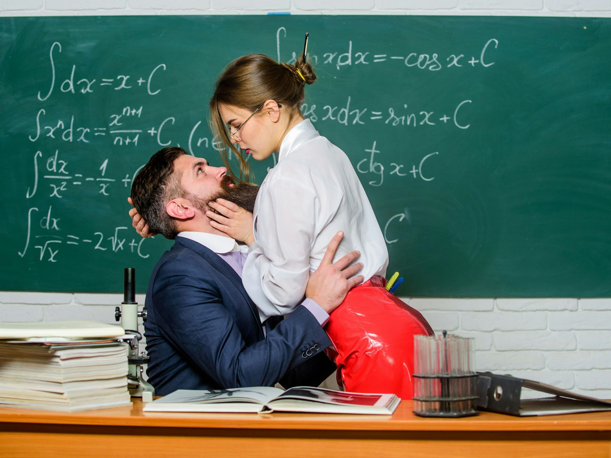 Lehrer und Schülerin flirten vor der Tafel.