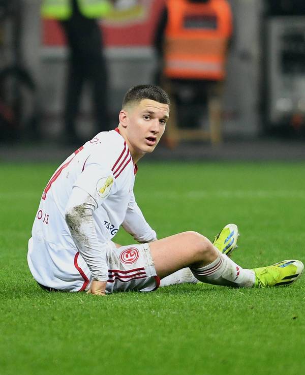 Fortuna Düsseldorfs Christos Tzolis sitzt im Pokalspiel bei Bayer Leverkusen auf dem Rasen.