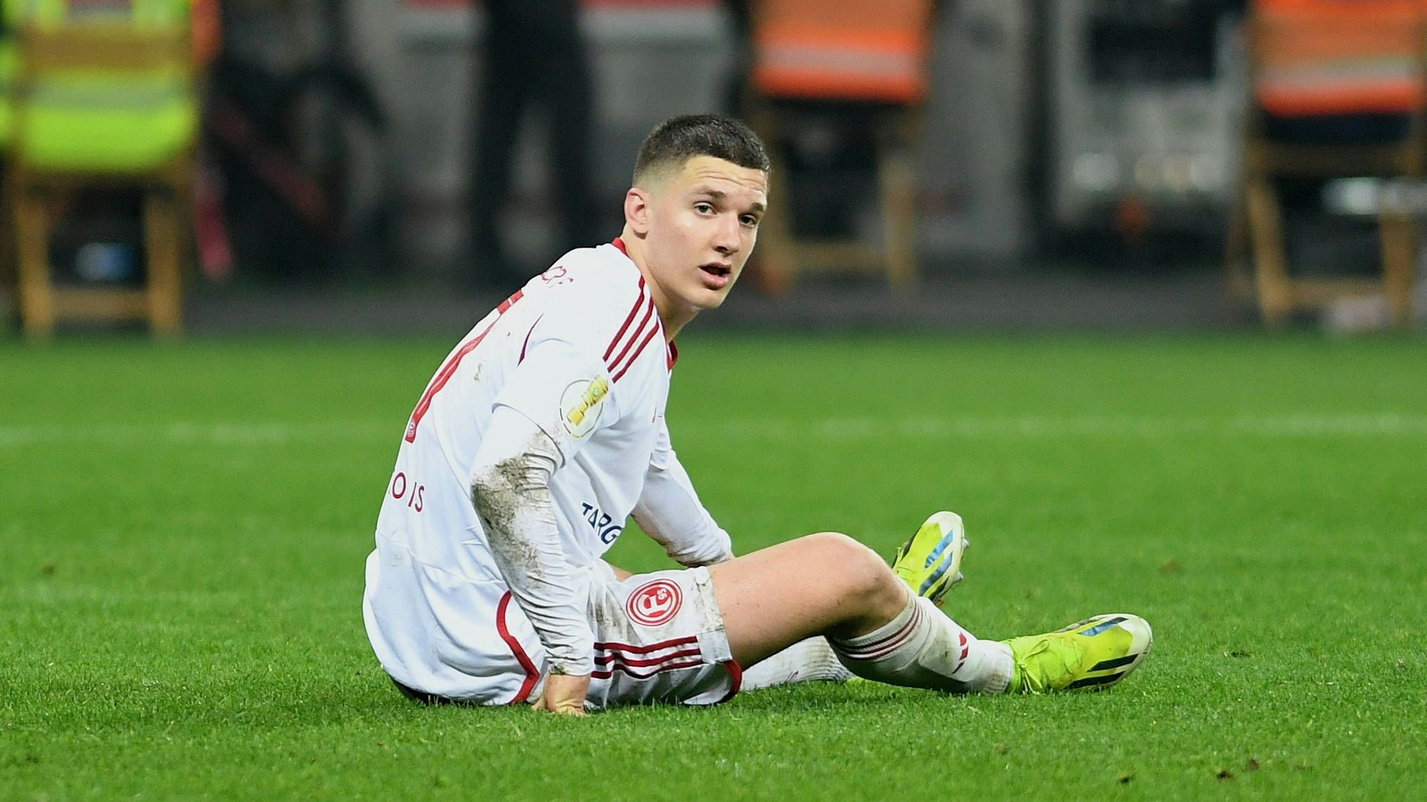 Fortuna Düsseldorfs Christos Tzolis sitzt im Pokalspiel bei Bayer Leverkusen auf dem Rasen.