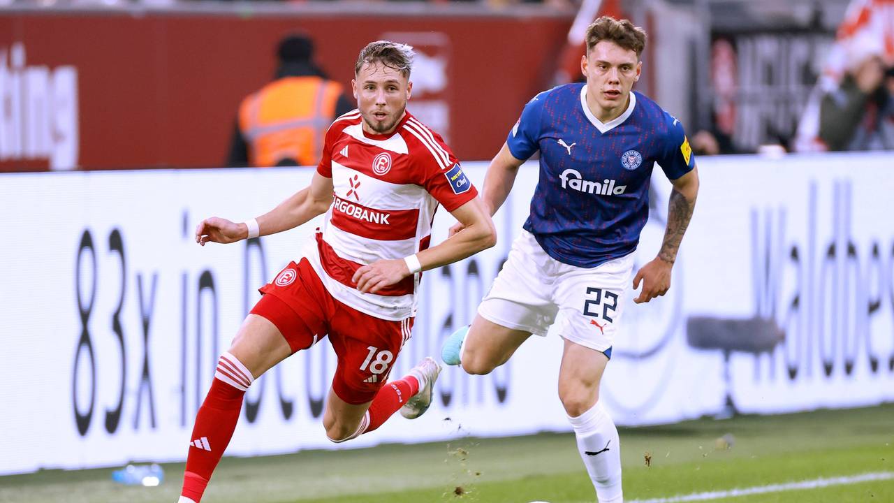 Fortuna Düsseldorfs Jona Niemiec und Kiels Nicolai Remberg blicken dem Ball hinterher.