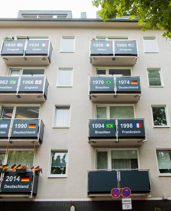 Blick auf die Fassade eines Hauses in Köln, auf denen die Weltmeister der bisherigen Fußball-WMs auf den Balkonen gezeigt werden.