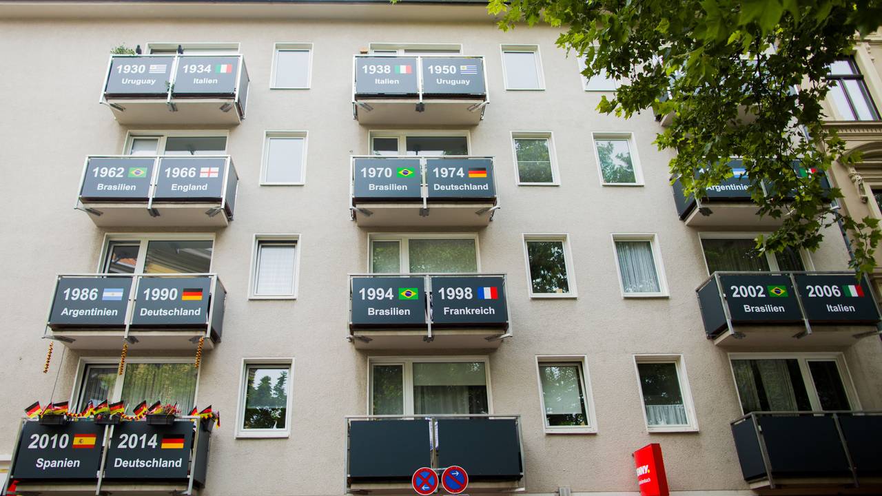 Blick auf die Fassade eines Hauses in Köln, auf denen die Weltmeister der bisherigen Fußball-WMs auf den Balkonen gezeigt werden.
