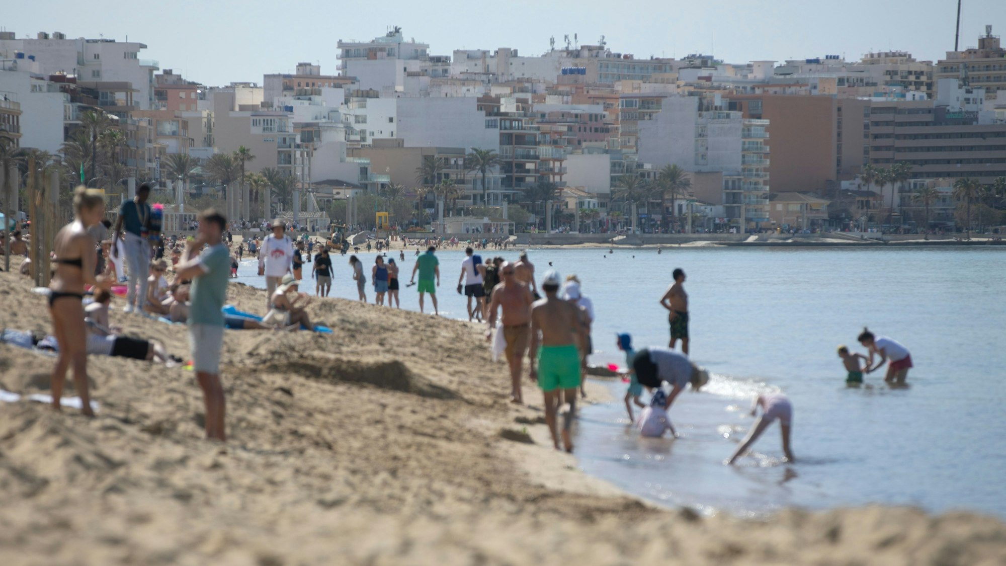 Menschen spazieren am Strand.