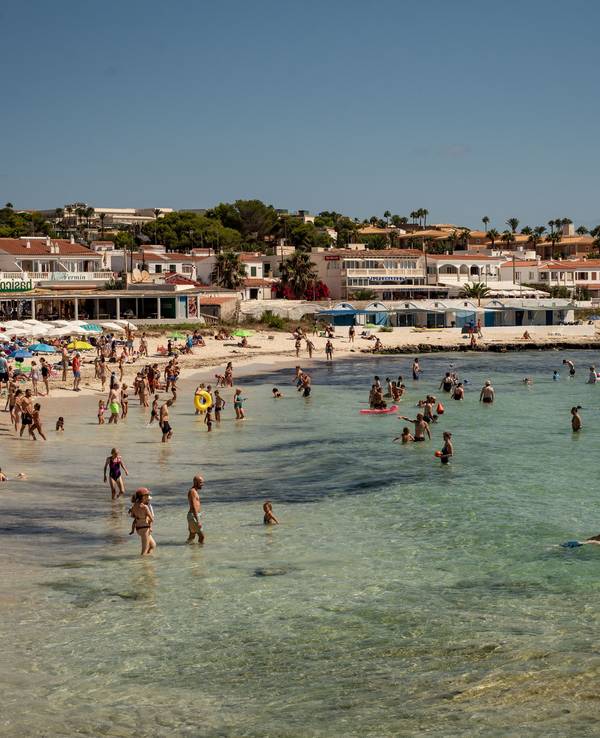 Urlauberinnen und Urlauber kühlen sich am Strand Punta Prima in Sant Lluis im Süden Menorcas im Wasser ab. Das Foto wurde im Sommer 2023 aufgenommen.
