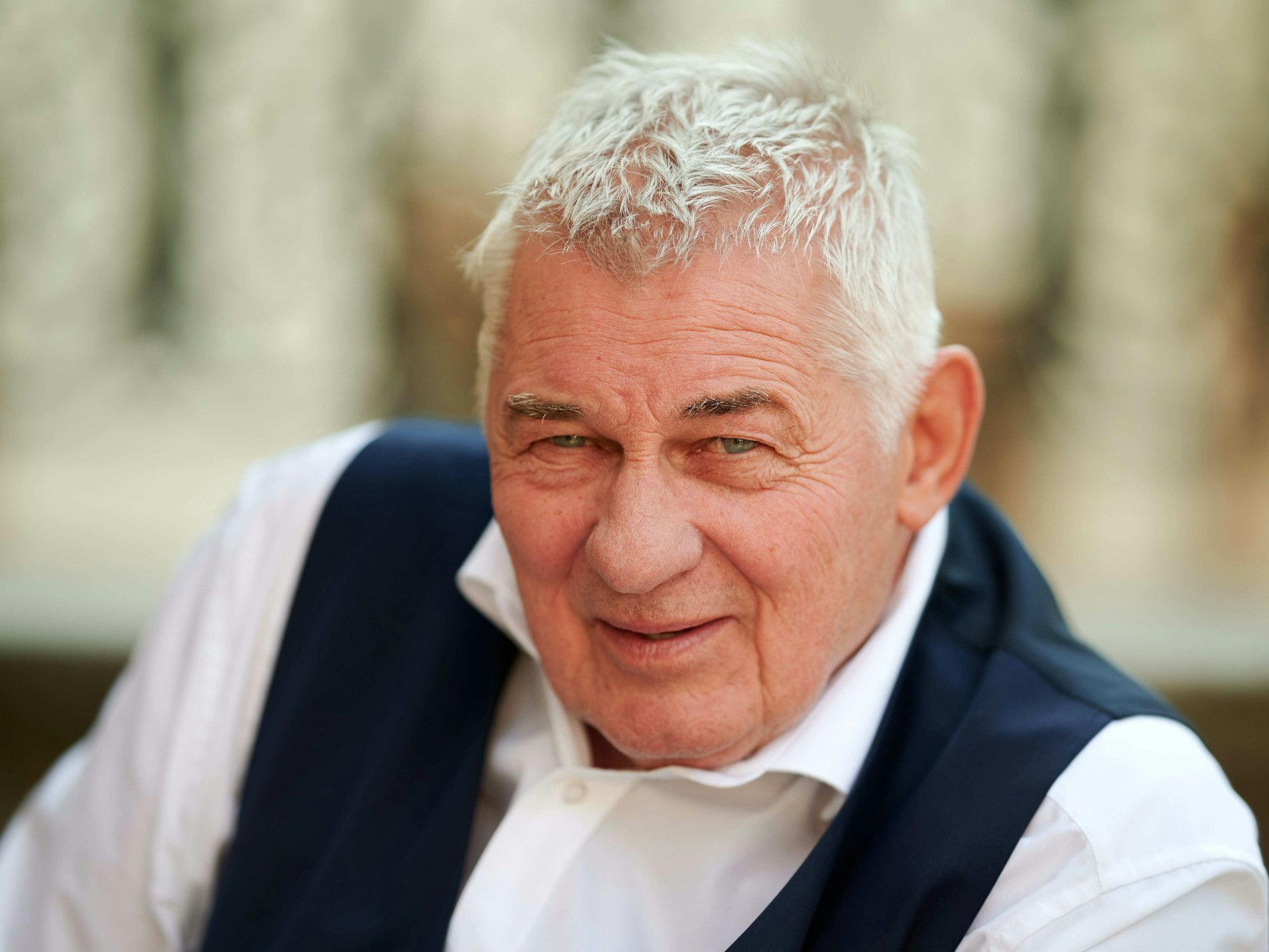 Der Schauspieler Heinz Hoenig sitzt bei einem Fototermin bei Dreharbeiten zur TVNOW Serie „Verbotene Liebe – Next Generation“ auf einer Treppe.