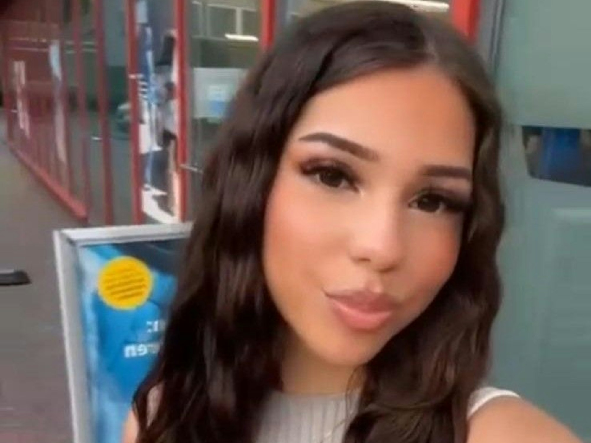 Eine junge Frau mit langen dunklen Haaren macht einen Kussmund für ein Selfie.