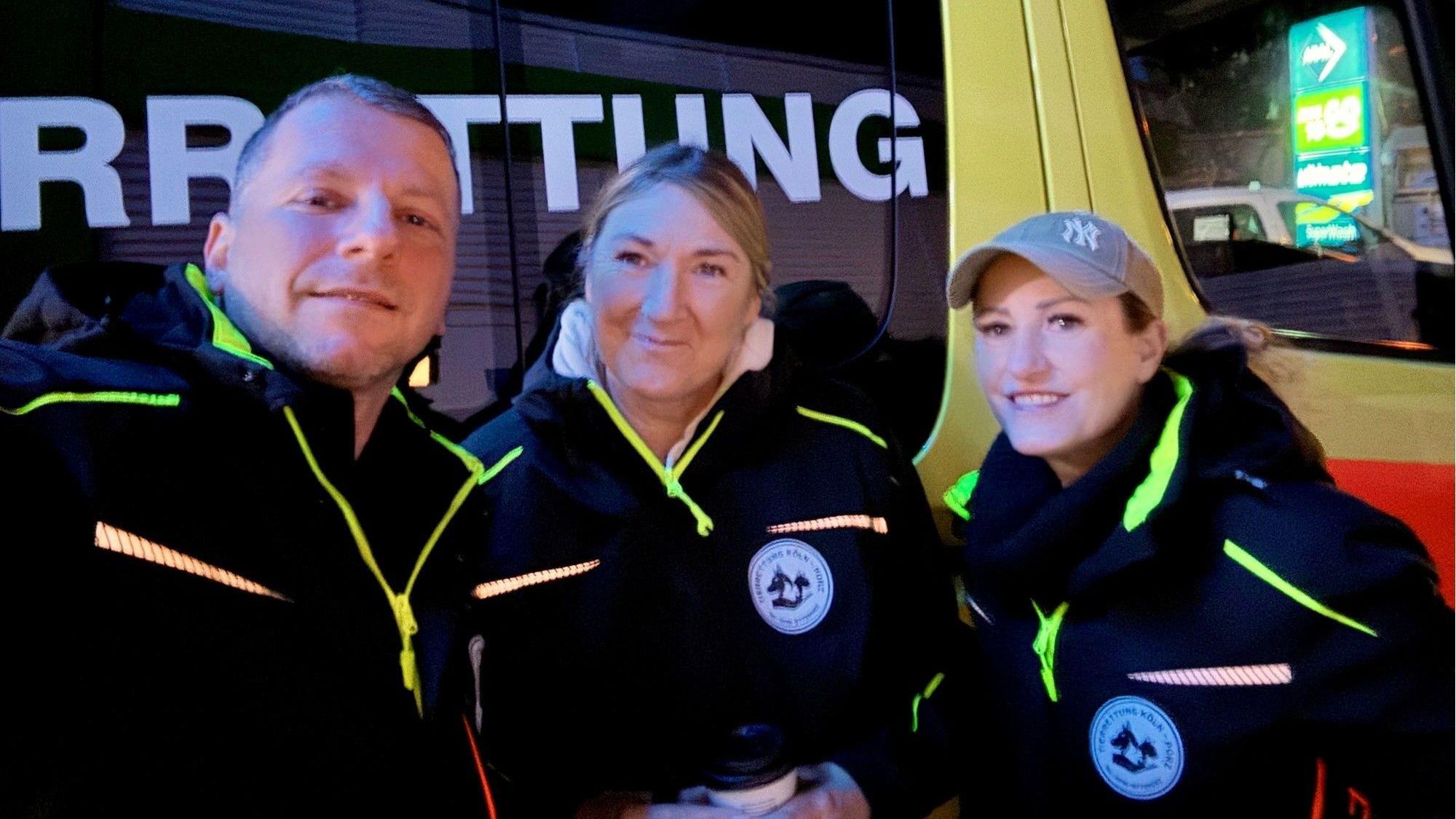 Ein Mann und zwei Frauen stehen vor einem Fahrzeug mit der Aufschrift Tierrettung.