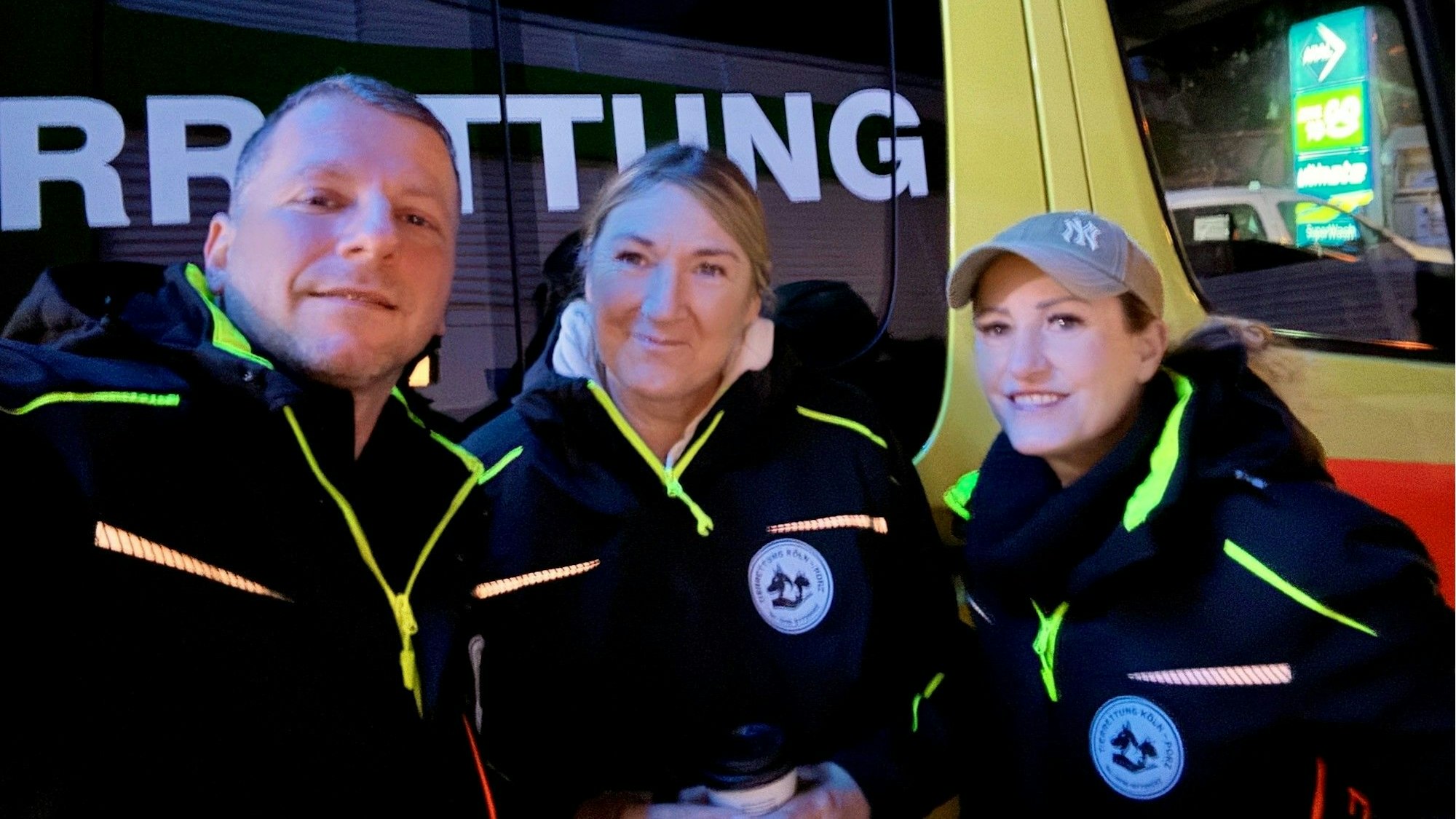 Ein Mann und zwei Frauen stehen vor einem Fahrzeug mit der Aufschrift Tierrettung.