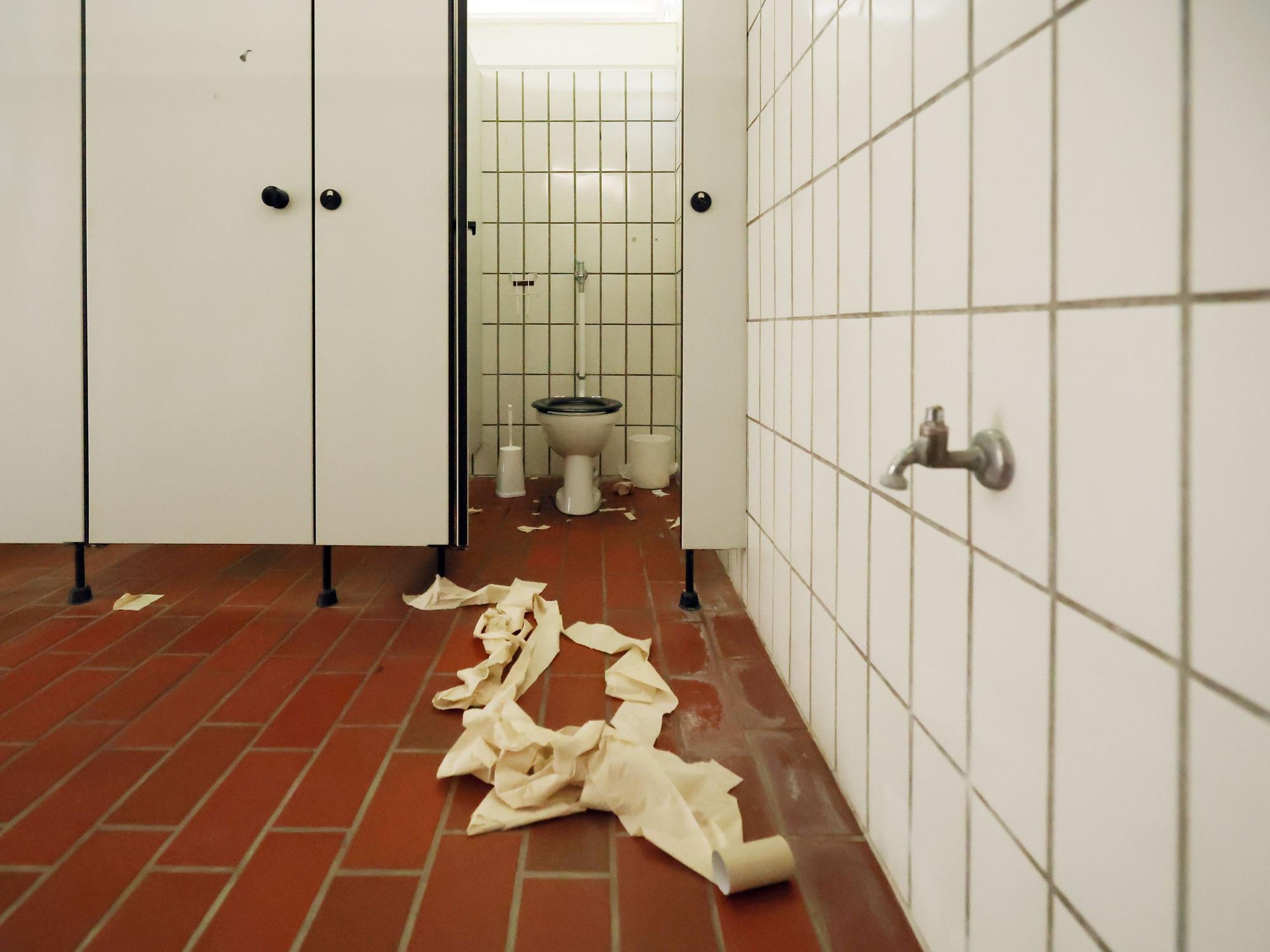 Vor einer Toilette liegt eine ausgerollte Klorolle auf dem Boden.