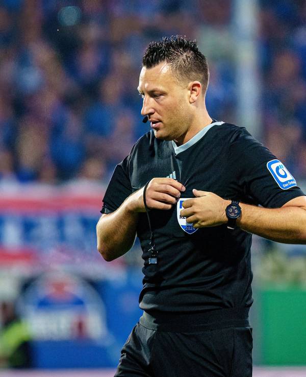 Schiedsrichter Sven Jablonski steht auf dem Platz und steckt seine Karten in die Brusttasche.