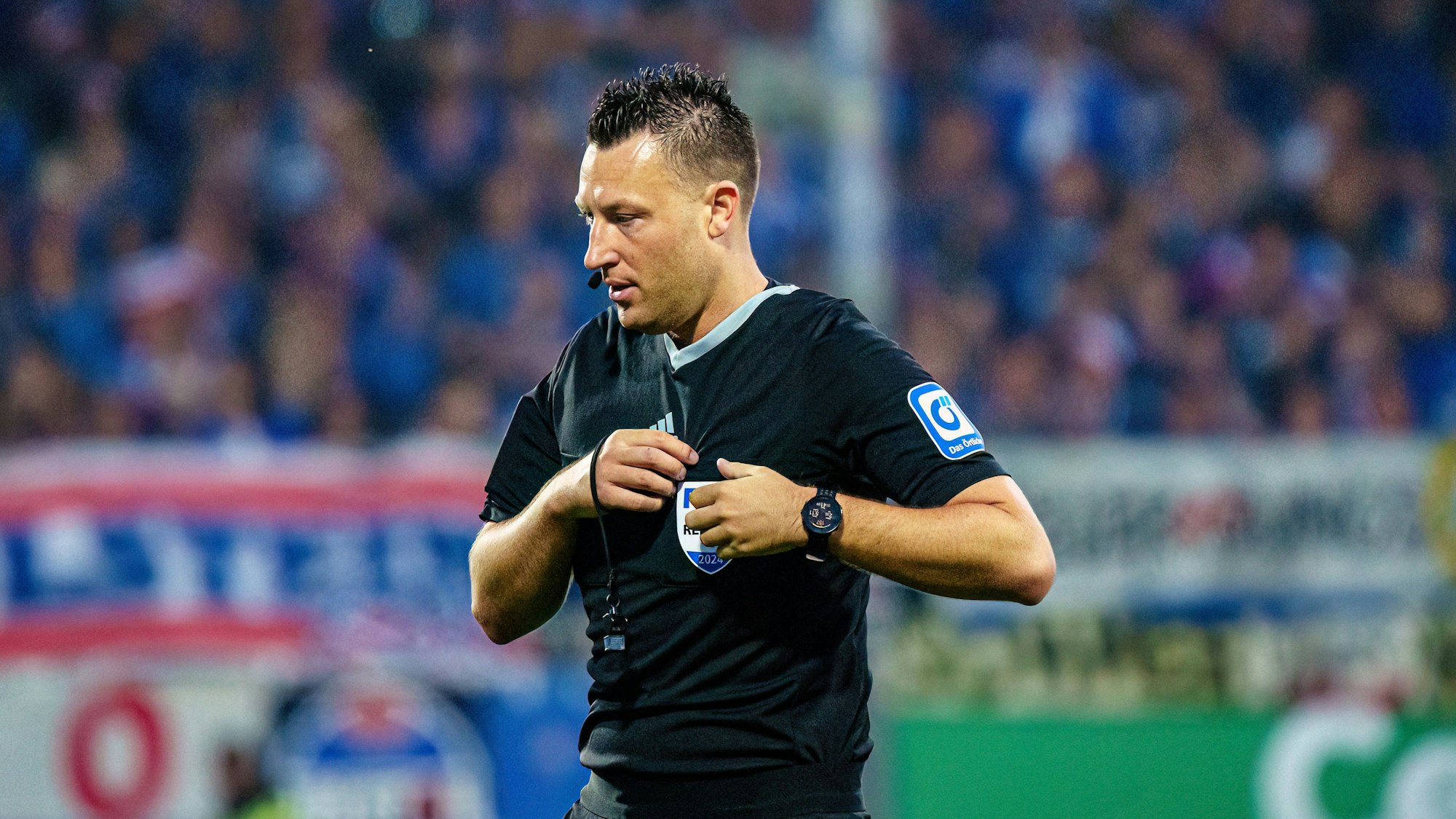 Schiedsrichter Sven Jablonski steht auf dem Platz und steckt seine Karten in die Brusttasche.