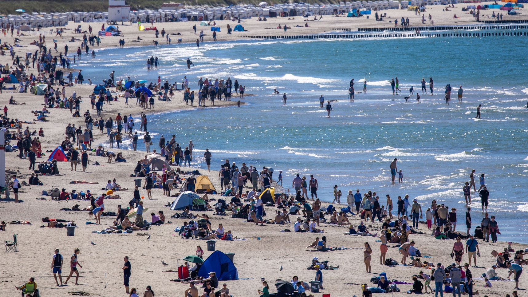 Urlauberinnen, Urlauber und Tagesgäste nutzen das sonnige, warme Wetter am 12. Mai zu einem Strandbesuch an der Ostseeküste in Warnemünde. Forschende schlagen Alarm: Unter dem Sand der Ostsee schlummert ein gefährliches Gift.dpa